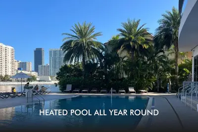 a heated pool all year round with palm trees at Your Beach Escape Starts Here, Studio for Families in Hallandale Beach