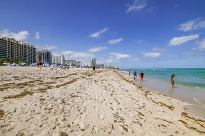 a group of people walking on the beach at Steps 2 Beach, Ocean Drive Deco Apt w/2 Queen Beds in Miami Beach