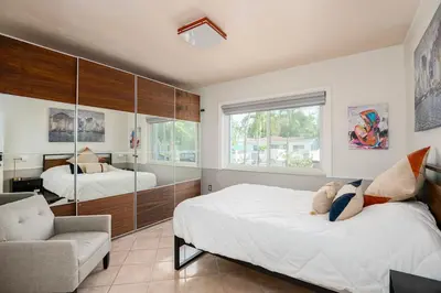 a bedroom with two beds and a chair and a mirror at Surfers Cove - Modern 3 2 w Pool near Calle 8 in Miami