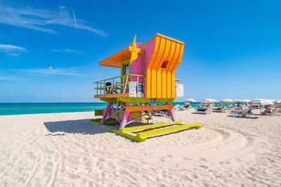 a lifeguard tower on a beach with chairs and umbrellas at Steps 2 Beach, Prime Ocean Dr Condo w/2 Queen Beds in Miami Beach