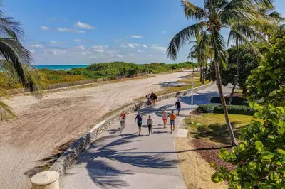 a group of people walking on a sidewalk next to the beach at Steps 2 Beach, Prime Ocean Dr Condo w/2 Queen Beds in Miami Beach