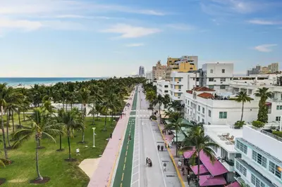 an empty city street with palm trees and the ocean at Private Ocean Dr Apt w/2 Queen Beds, Steps 2 Beach in Miami Beach