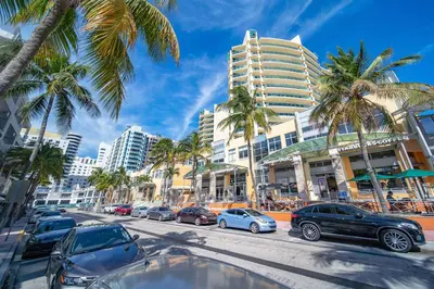 a city street with parked cars and palm trees at Super Beach Deal, Apt w/2 Queen Beds On Ocean Dr in Miami Beach