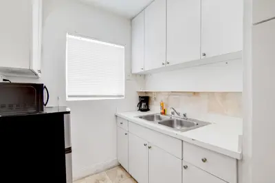 a white kitchen with a sink and a microwave at Stylish Ocean Dr Apt w/ 2 Queen Beds, Across Beach in Miami Beach