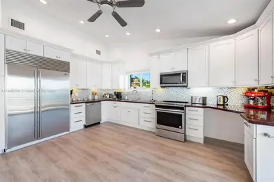 a kitchen with white cabinets and a ceiling fan at Villa Hashmi Luxury 5BD & 5BA Retreat on North Bay Island in Miami Beach