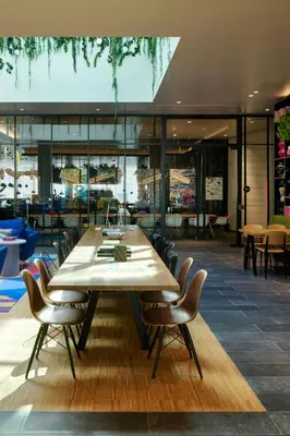 a large wooden table in a restaurant with chairs at citizenM Miami South Beach in Miami Beach