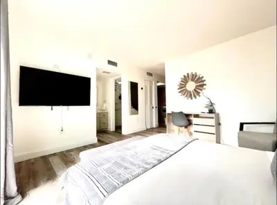 a white bedroom with a large bed and a flat screen tv at Miami International Airport 1 in Miami
