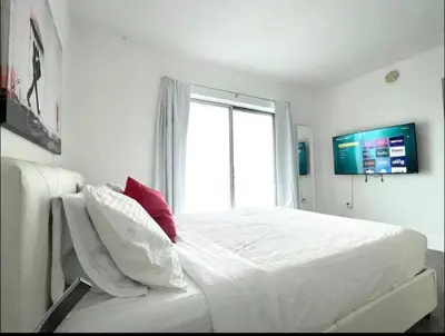 a white bedroom with a large bed with a window at Miami International Airport 1 in Miami