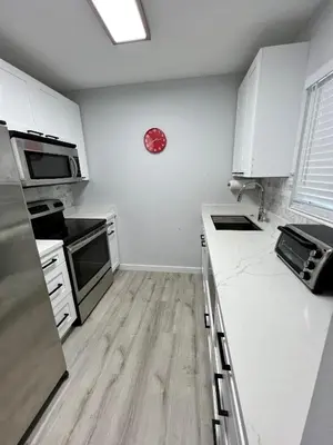 a kitchen with white cabinets and a clock on the wall at Villa Michloe - Steps from Wilton Drive in Fort Lauderdale