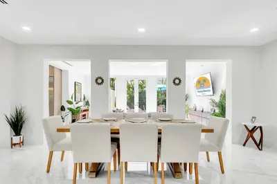 a dining room with a table and white chairs at Villa Tropicale Stunning 4 Bedroom 4 Bath Home with Pool and BBQ in Miami