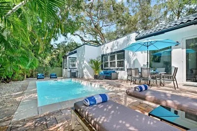 a house with a swimming pool with a table and an umbrella at Villa Tropicale Stunning 4 Bedroom 4 Bath Home with Pool and BBQ in Miami