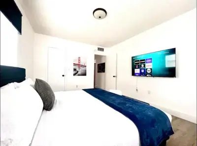 a white bedroom with a large bed and a flat screen tv at Miami International Airport 2 in Miami