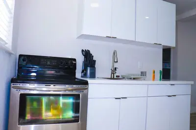 a kitchen with a stove and white cabinets at Flamingo Beach House in Dania Beach
