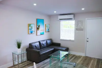 a living room with a leather couch and a glass table at Flamingo Beach House in Dania Beach