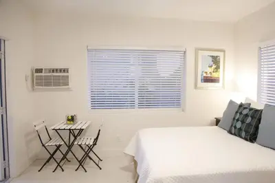 a white bedroom with a bed and a table and chairs at Apt 6 Miami Designer Studio in the Upper East-Side in Miami
