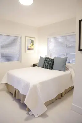 a white bedroom with a large white bed with two windows at Apt 6 Miami Designer Studio in the Upper East-Side in Miami