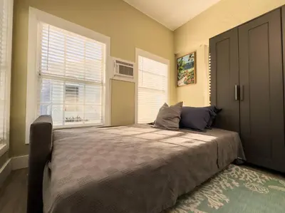 a bedroom with a large bed and two windows at Shenandoah Victorian Suite with TV's in every room in Miami