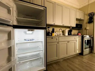 an open refrigerator in a kitchen with white cabinets at Shenandoah Victorian Suite with TV's in every room in Miami