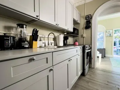 a kitchen with white cabinets and a counter top at Shenandoah Victorian Suite with TV's in every room in Miami