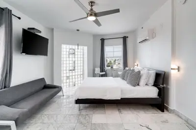 a white bedroom with a bed and a couch at Best Location SOBE Top Floor 2 min to beach & fun in Miami Beach