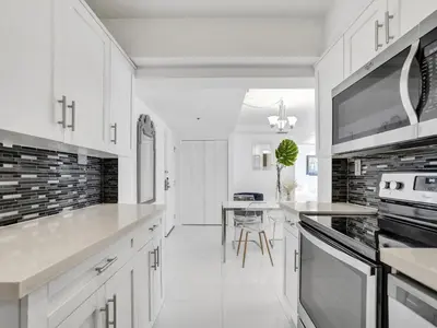 a white kitchen with white cabinets and a table at Amazing Ocean View Condo Beach Service 1111 in Miami Beach
