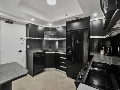 a kitchen with black cabinets and a black refrigerator at Spacious Ocean View Condo Beach Service 803 in Miami Beach