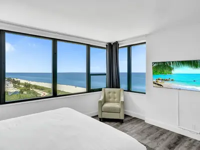 a bedroom with a bed and a chair and the ocean at Full ocean view Huge private terrace 1002 in Miami Beach
