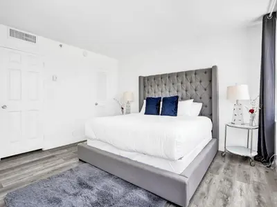 a white bedroom with a large bed with blue pillows at Full ocean view Huge private terrace 1002 in Miami Beach
