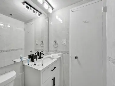 a white bathroom with a shower and a sink at Huge 2BD Miami beach with beach service - 720 in Miami Beach