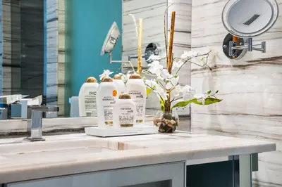 a bathroom sink with three bottles of soap and flowers at Oceanview Private Home at South Beach-814 in Miami Beach
