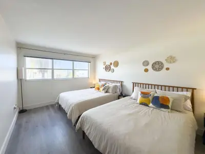 two beds in a room with white walls and a window at The Octagon in South Beach in Miami Beach