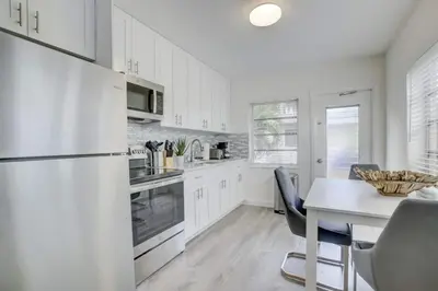 a kitchen with white cabinets and a table with chairs at Pool Access Free Parking Smart TV Wifi in Fort Lauderdale