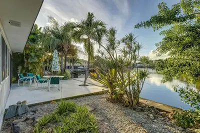a house with a patio with chairs and a body of water at Waterfront Apartment Private Patio Pool in Fort Lauderdale