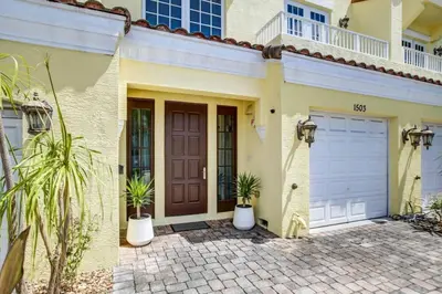 a house with a brown door and two potted plants at Private Patio Cali King Bed Walk to Las Olas in Fort Lauderdale