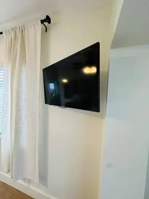 a flat screen tv on a wall with a curtain at Miami Coral Gables Studio near Airport and Beaches in Miami