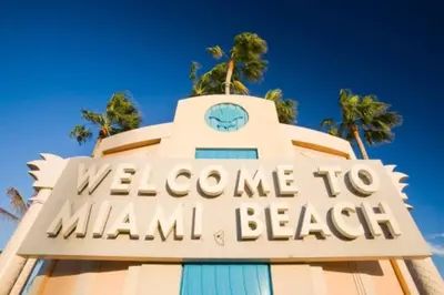 a welcome to miami beach sign with palm trees in the background at BEST DEAL! 2 Bedroom Modern Beachfront by YouRent! in Miami Beach