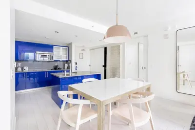 a kitchen with blue cabinets and a white table and chairs at 2BR W Residence, FLL Beach, Oceanside, pools, hot tub, bar credit in Fort Lauderdale