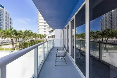 a balcony with chairs and palm trees on a building at 2BR W Residence, FLL Beach, Oceanside, pools, hot tub, bar credit in Fort Lauderdale