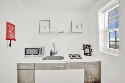 a white kitchen with a sink and a microwave at Hotel Belleza in Miami Beach