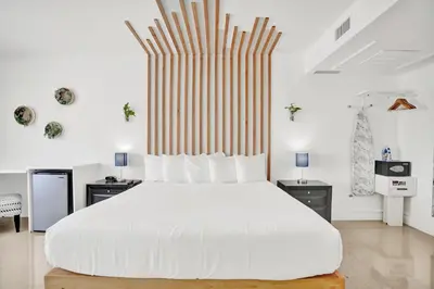 a white bedroom with a large white bed and two tables at Hotel Belleza in Miami Beach