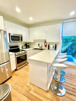 a kitchen with white cabinets and a large window at 30 GUESTS LUXURY SOUTH BEACH SUITES w ROOFTOP in Miami Beach