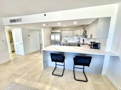 a large kitchen with two chairs at a counter at Oceanfront Beach Retreat Beach Service 502 in Miami Beach