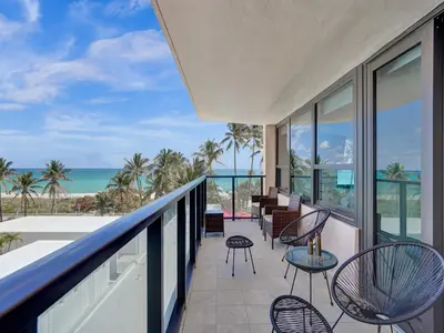a balcony with chairs and tables and a view of the ocean at Oceanfront Beach Retreat Beach Service 502 in Miami Beach
