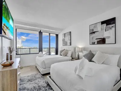 a white bedroom with two beds and a large window at Oceanfront Beach Retreat Beach Service 502 in Miami Beach