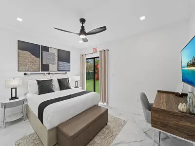 a bedroom with a bed with a ceiling fan and a desk at Spacious home w heated pool jacuzzi in Hollywood