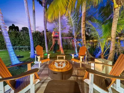 a patio with palm trees and a table and chairs at Spacious home w heated pool jacuzzi in Hollywood