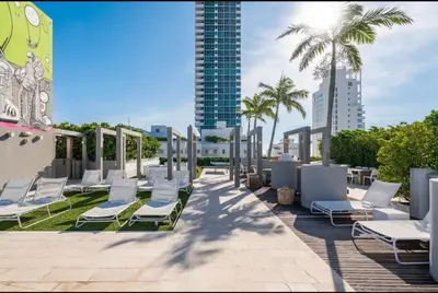 a row of lounge chairs and palm trees on a patio at Hotel Miami Beach Convention Center in Miami Beach