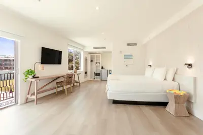 a white bedroom with a bed and a desk and a television at Casa SOBE in Miami Beach