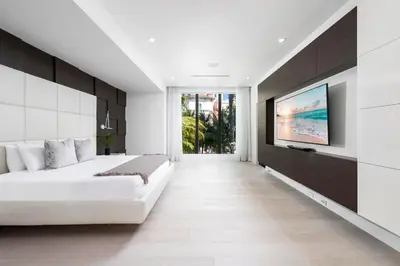 a bedroom with a white bed and a flat screen tv at Villa Celine in Fort Lauderdale