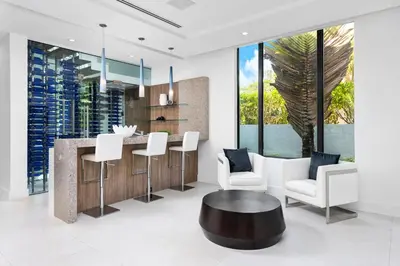 a kitchen with a bar with white chairs and a table at Villa Celine in Fort Lauderdale